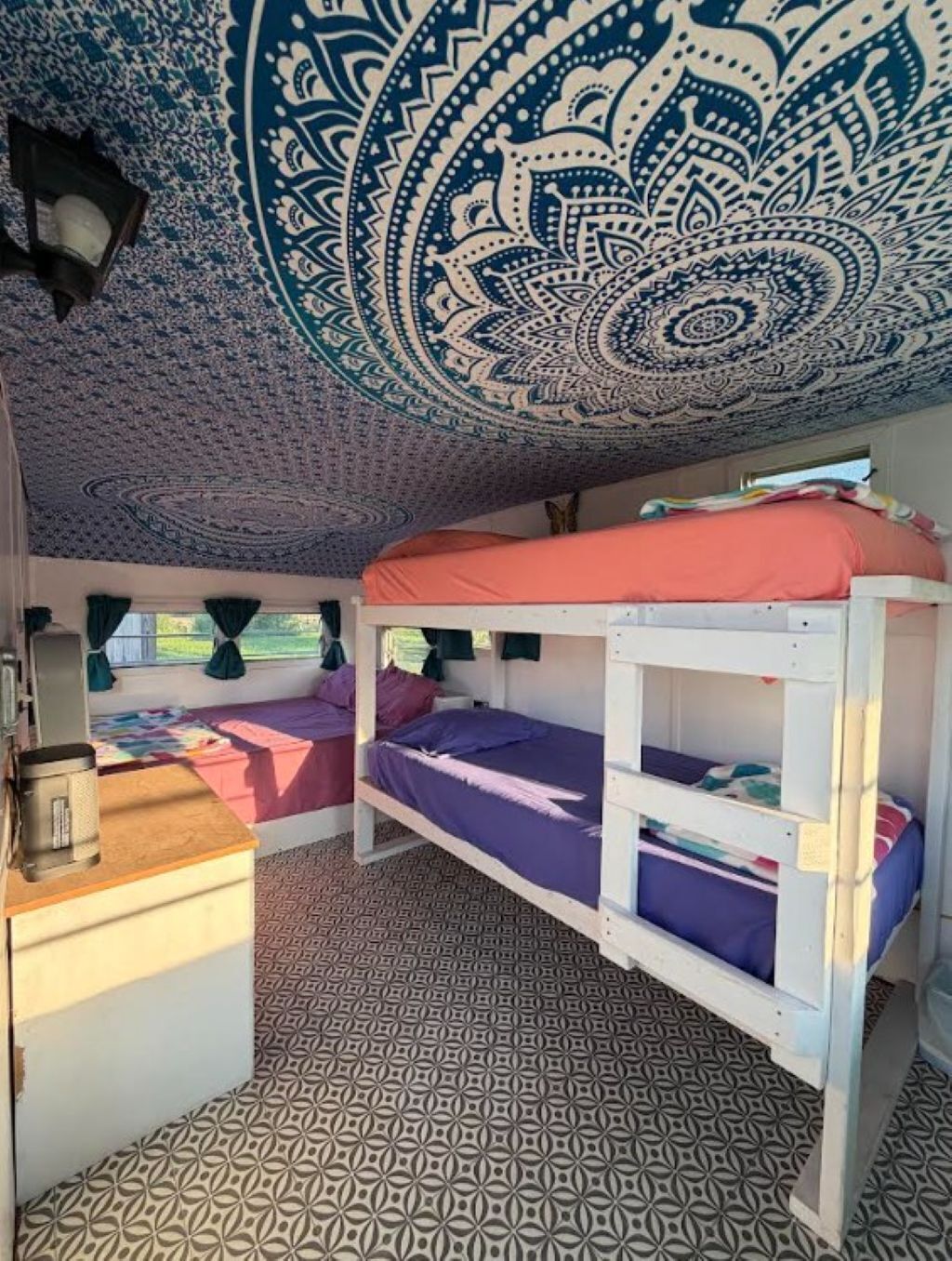 Een kamer met een stapelbed, een kamerbreed tapijt met dessin en wanddecoratie aan het plafond.