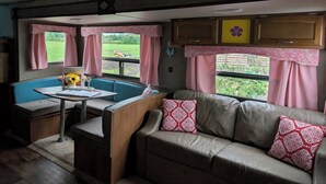 Interior acogedor de una autocaravana, con kitchenette, zona de estar y ventanas amplias que ofrecen vistas al exterior.