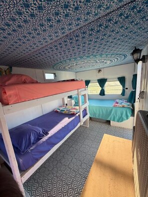 Habitación con literas, techo estampado, ventana con cortinas y suelo con diseño.