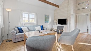 Ein modernes Wohnzimmer mit einer Couch, zwei Sesseln, einem Couchtisch, einem Fernseher und einer Karte an der Wand.