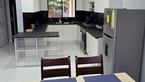 Una cocina moderna con armarios blancos, una mesa de comedor con individuales azules y un refrigerador.