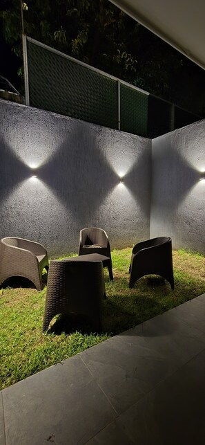 An outdoor seating area with wicker chairs and a concrete wall with embedded lights. - Hermosa casa en la ciudad de Santa Ana El Salvador (Santa Ana)