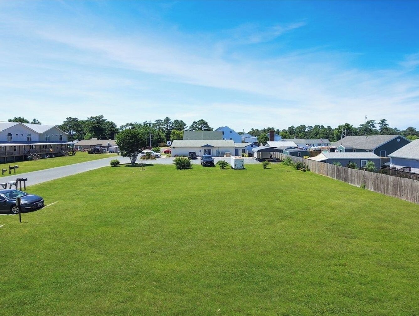 A residential area with houses, a grassy lawn, and a paved driveway.