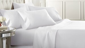 A neatly made bed with white linens and pillows, a round side table with a vase of flowers, and a classic chair. - Central Location~Walk 2 Dining! Beach Pass & Gear! (Chincoteague)