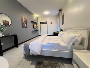 Una habitación de hotel moderna con una cama grande, una mesita de noche, un escritorio y una silla.