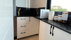 Una cocina moderna con armarios blancos, encimera negra y ventana con vistas a zonas verdes.