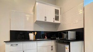 A modern kitchen with white cabinets, a black countertop, and a stainless steel refrigerator. - Kulambiro Cozy Studio - City Stay (Kampala)