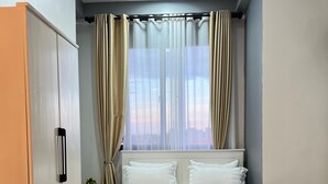 A bedroom with a bed, curtains, a wardrobe, and a window. - Kulambiro Cozy Studio - City Stay (Kampala)