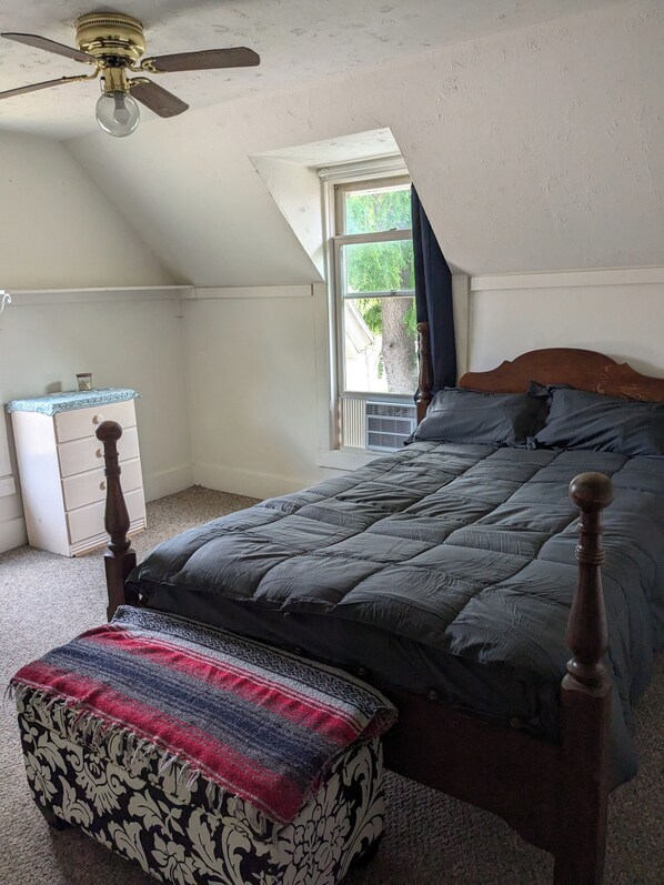 A bedroom with a bed, a wooden dresser, a window with a view of trees, and a ceiling fan. - Cozy 2-bedroom apartment with WiFi, AC in welcoming Spring Green (Spring Green)