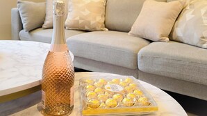 Un salon avec une table basse en marbre, une bouteille et un plateau de chocolats.