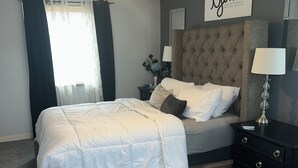 Een slaapkamer met een bed, nachtkastje, plafondventilator en een motiverende quote op de muur.