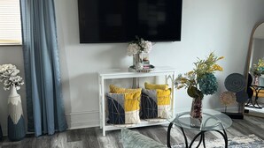 Een woonkamer met een bank, een salontafel, een televisie en decoratieve objecten.