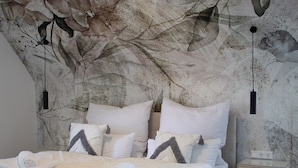 A modern bedroom with a large bed, a nightstand, and a wall mural.