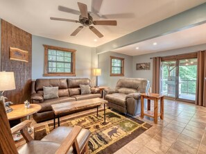 A living room with a brown leather sofa, a brown leather chair, a wooden coffee table, and a patterned rug.
