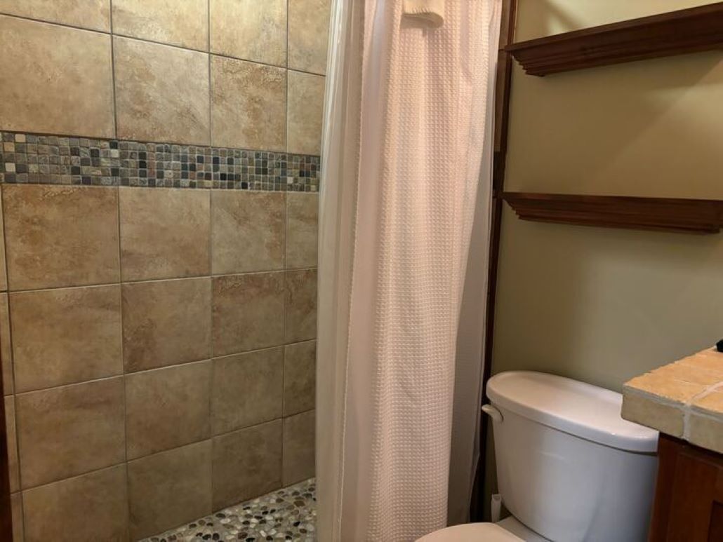 A bathroom with a shower area, tiled walls, and a toilet.