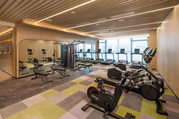 A gym with exercise equipment, mirrors, and a checkered floor.