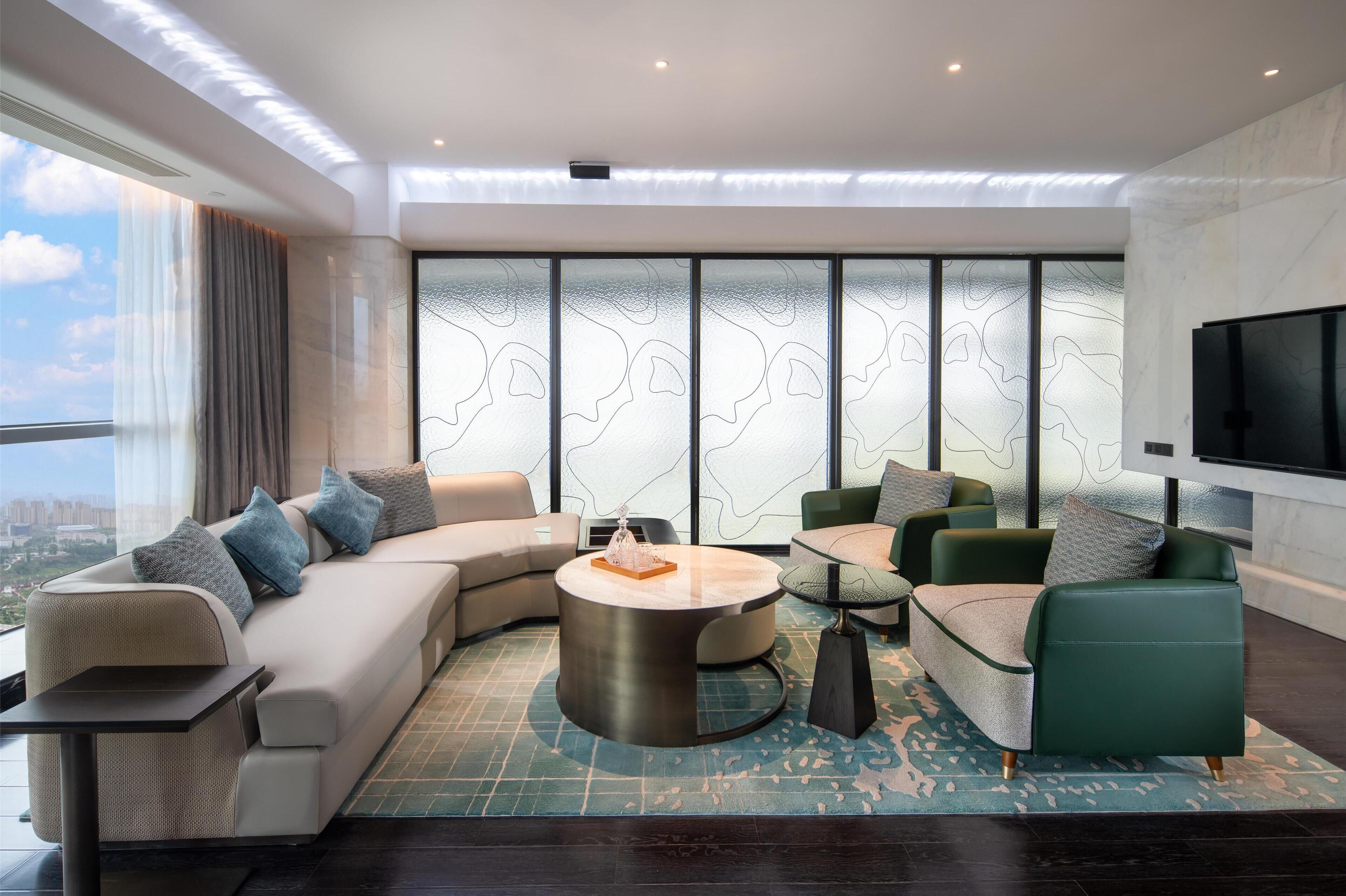 A modern living room with a sectional sofa, a round coffee table, and a TV mounted on the wall.
