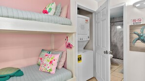 Un dormitorio con literas, lavadora y baño con letrero de prohibido fumar.