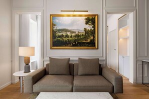 A modern living room with a large landscape painting, a sofa, a side table, and a lamp. - Dolce By Wyndham Versailles - Domaine Du Montcel (Jouy-en-Josas)