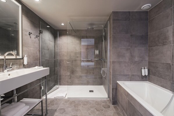 Un baño moderno con un espejo grande, una bañera blanca, una zona de ducha y un tocador con lavabo.