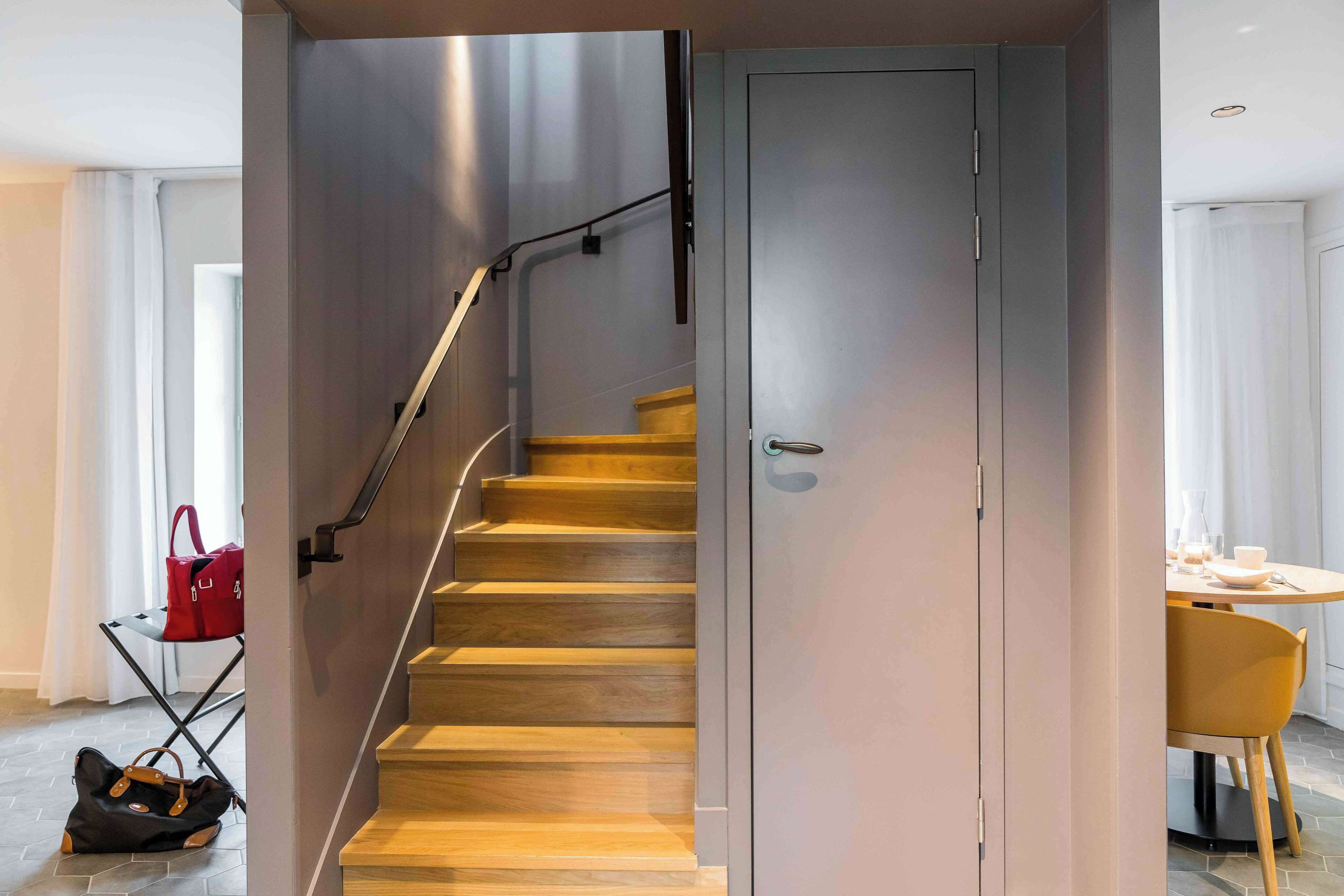 A staircase with a metal handrail and wooden steps leading to a closed door.