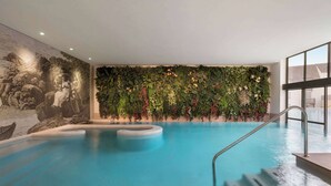 Una piscina interna con un murale su una parete e una parete verde con piante.