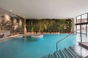 An indoor swimming pool with a mural on one wall and a green wall with plants.