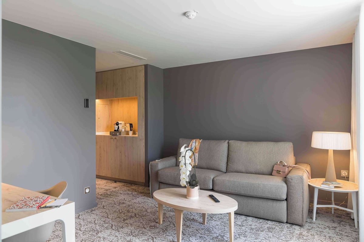 A modern living room with a grey sofa, a round coffee table, and a small side table with a lamp.