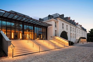 A hotel entrance with a glass facade, a covered outdoor area, and a set of stairs leading to the entrance.