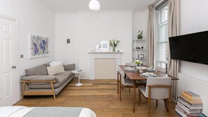 Een moderne, compacte leefruimte met een bank, eettafel en televisie.