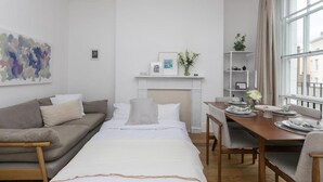 Een moderne slaapkamer met een bed, een bank, een eettafel gedekt voor twee personen en een open haard.