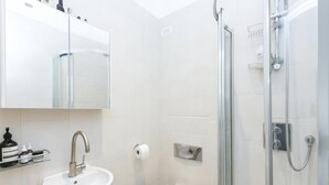 Een moderne badkamer met een wastafel, toilet en douche.