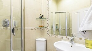 A bathroom with a glass-enclosed shower, a white toilet, and a sink with a mirror above it. - Charming London City Apartment (London)