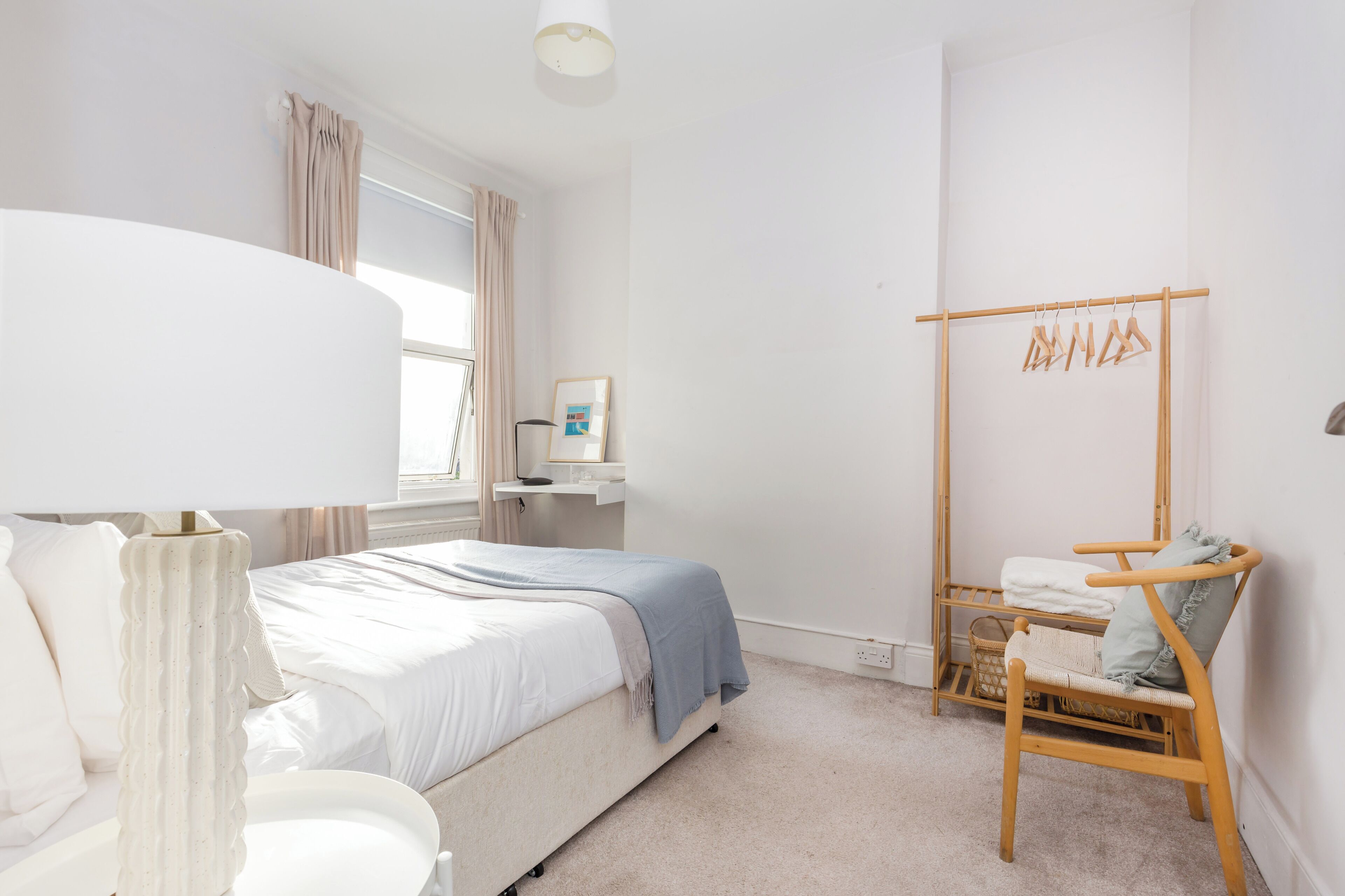 Una camera da letto con un letto, un comodino, una lampada e una sedia di legno.