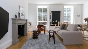 A living room with a fireplace, a sofa, a coffee table, and a side table. - Generously Large 1 Bedroom Apartment in Farringdon (London)