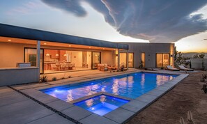Une maison moderne dotée d’une piscine, d’un espace salon extérieur et offrant une vue sur un paysage désertique.