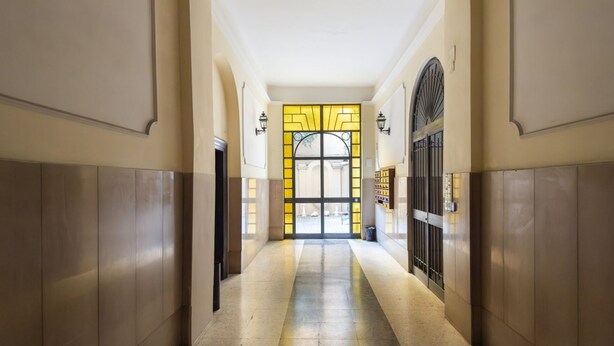 A hallway with a tiled floor, a glass door with yellow accents, and a metal gate. - Vittorio Elegant Two Bedroom Apartment (Roma)