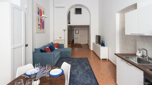 A compact living space with a dining area, kitchenette, and a staircase leading to an upper level. - Vittorio Elegant Two Bedroom Apartment (Roma)