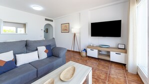 A modern living room with a sofa, TV, and a small table. - AlmeriaSuite Mojacar Breeze Sun101 (Mojacar)