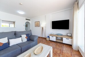 A modern living room with a sofa, TV, and a small table.