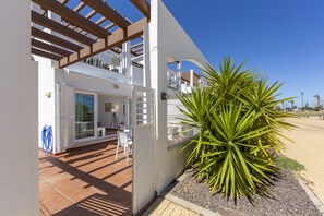 A modern house with a patio, a large plant, and a clear blue sky.