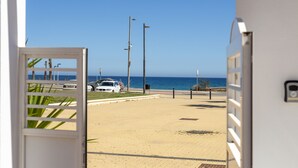 A beach view from a room with a door, a paved walkway, and a parked car. - AlmeriaSuite Mojacar Breeze Sun101 (Mojacar)