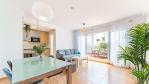 Un espace de vie moderne comprenant une table à manger en verre, un canapé et un coin cuisine.