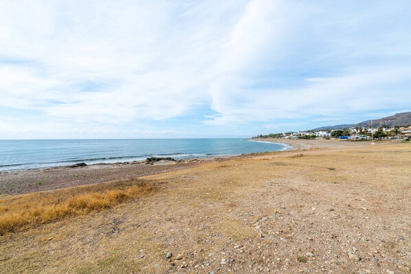 A coastal landscape with a beach, rocky terrain, and a distant town. - AlmeriaSuite Mojacar Breeze Sun108 (Mojacar)