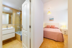 A bedroom with a bed, bedside tables, and a nightstand. - AlmeriaSuite Mojacar Breeze Sun108 (Mojacar)