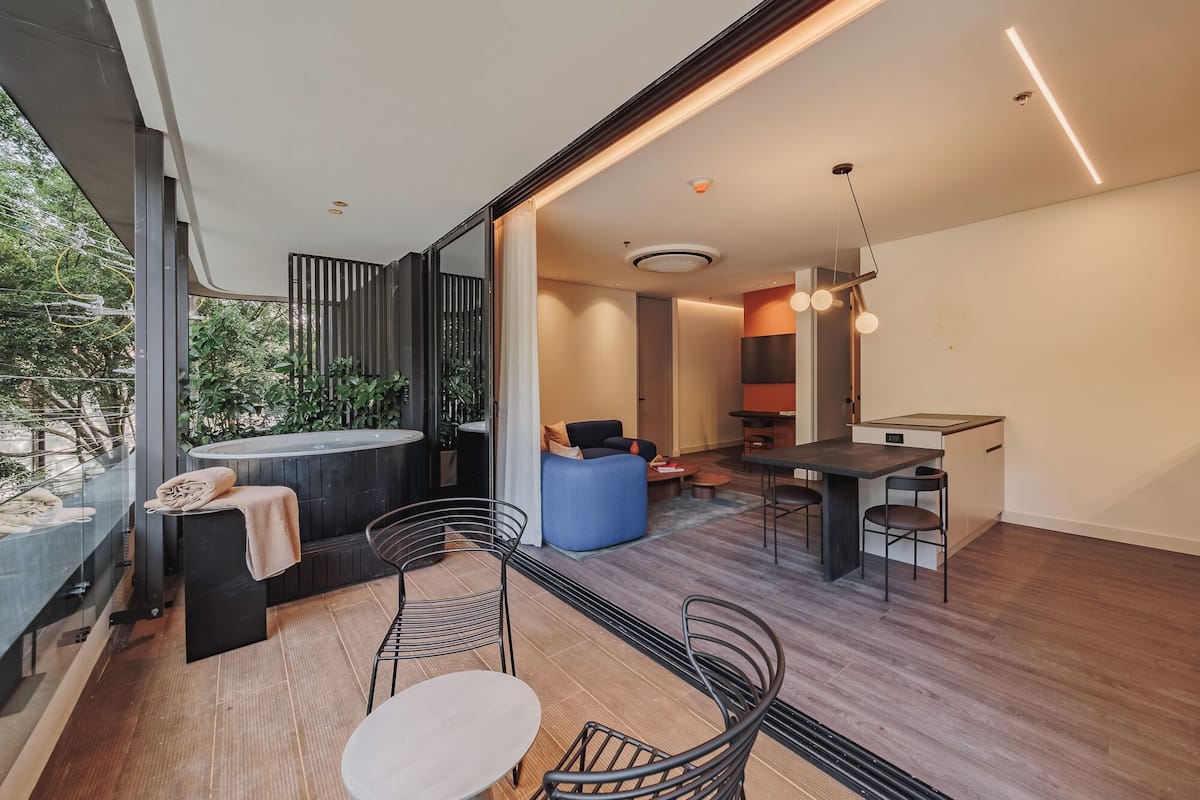 A modern interior with a dining area, seating, and a view of greenery outside.