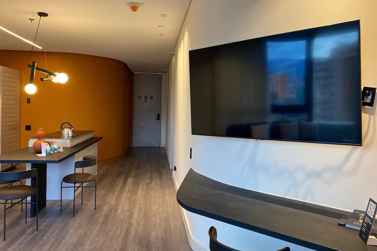 A modern interior with a dining area, a flat-screen TV mounted on the wall, and a wooden floor.