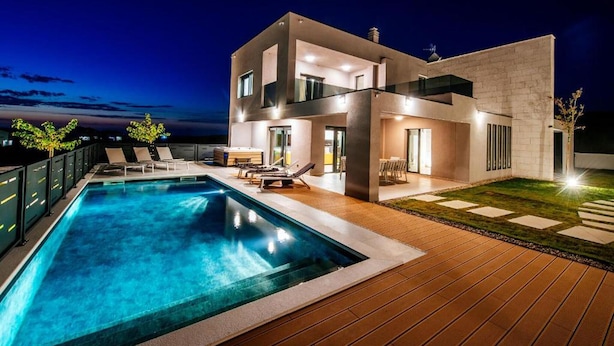 Uma casa moderna com dois andares, piscina, área de estar externa e um pátio bem iluminado.