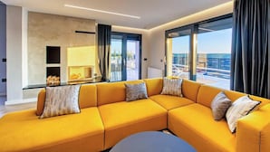 Uma sala de estar moderna com um sofá seccional amarelo, lareira e janelas amplas com vista para a cidade.