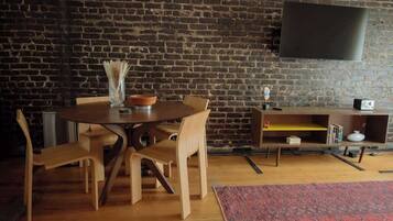 Een eetgedeelte met een bakstenen muur, een ronde houten tafel en stoelen.